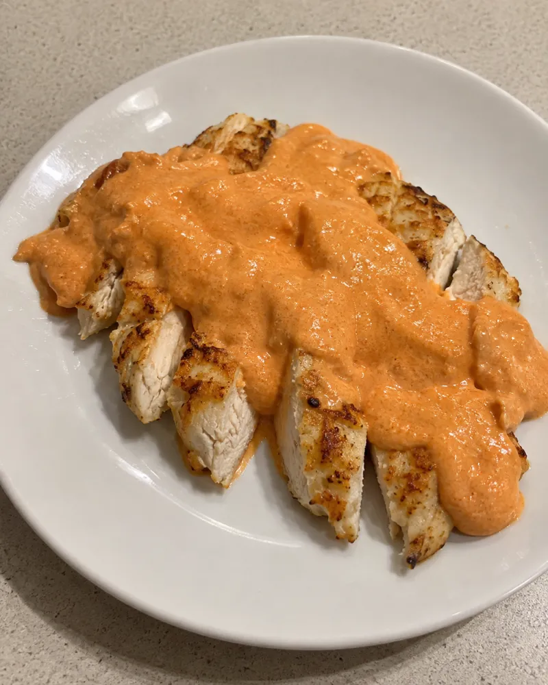 Pechuga de pollo a la plancha cortada en tiras y cubierta de una salsa cremosa naranja de pimientos del piquillo